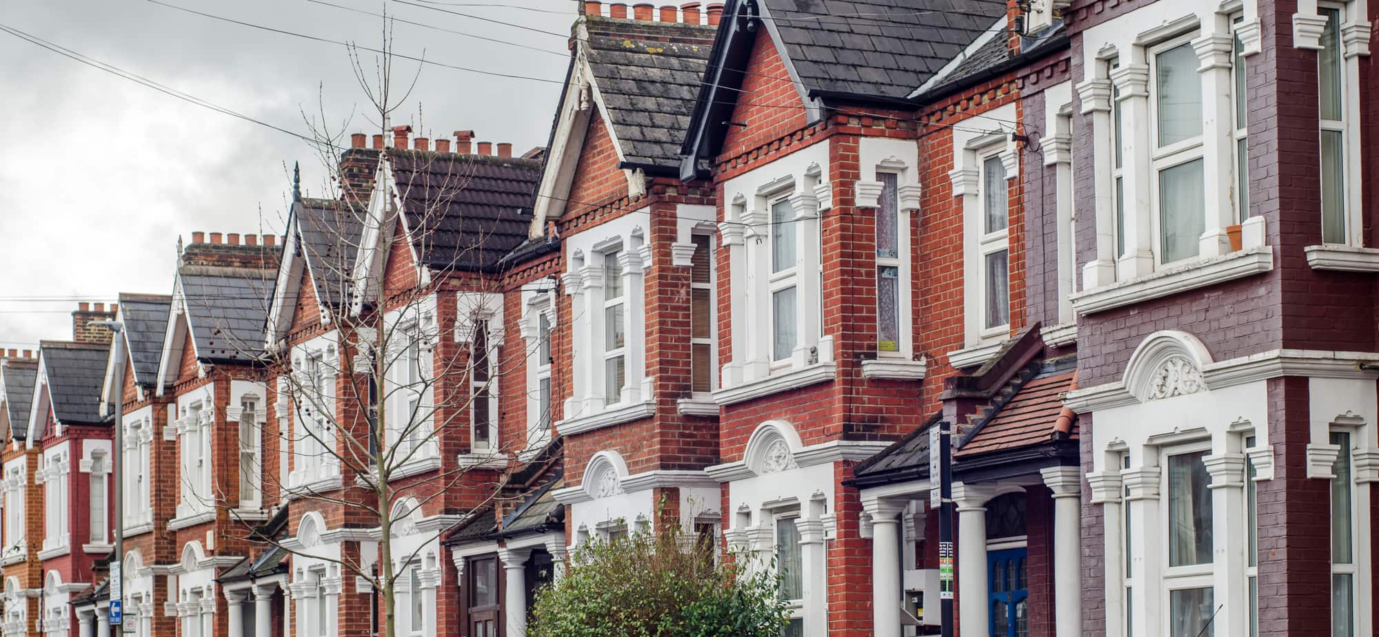 Row of red-brick terraced houses with gabled roofs and white window surrounds.