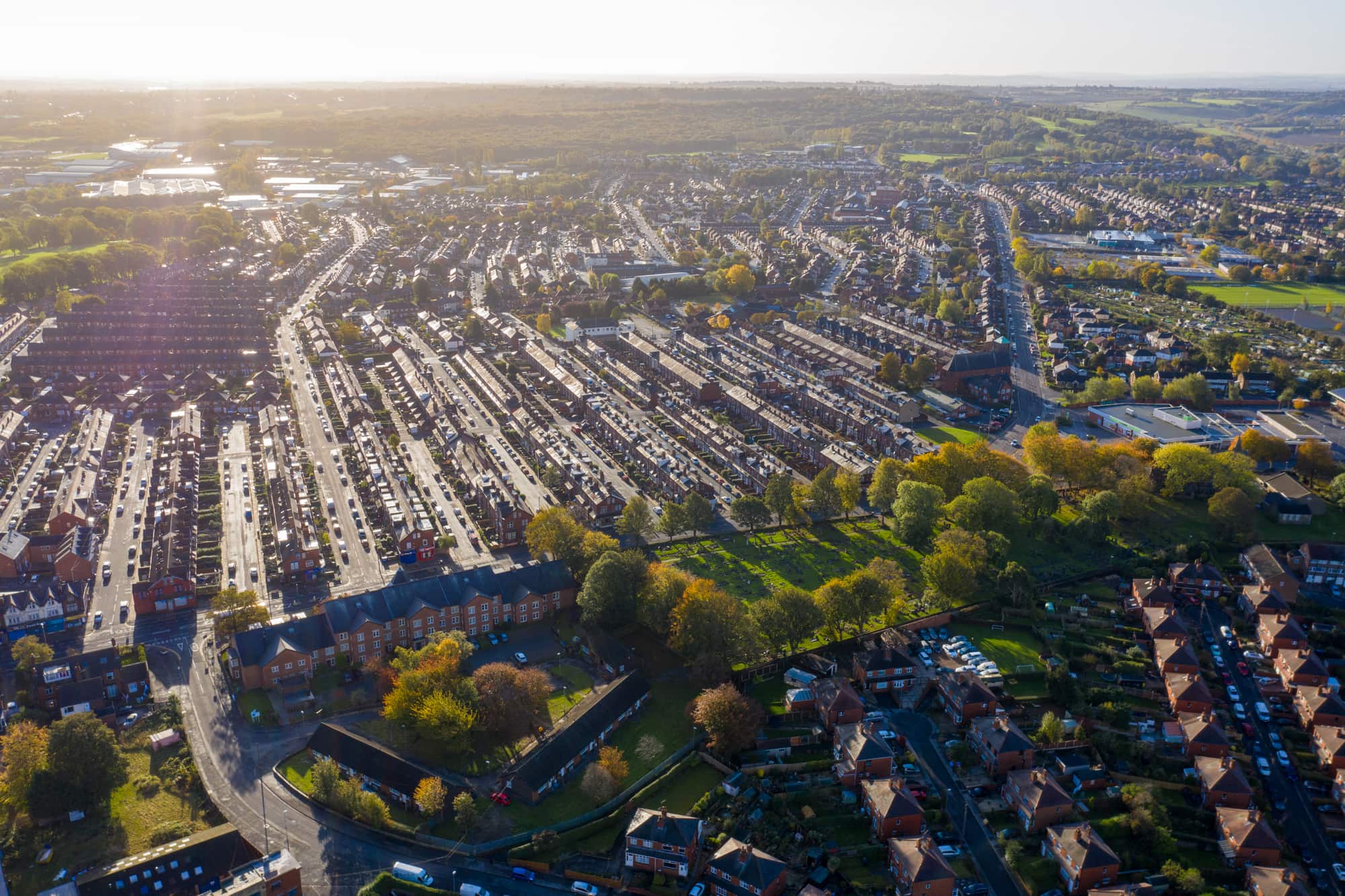 Sunlit aerial view of terraced streets and a tree-lined green space.
