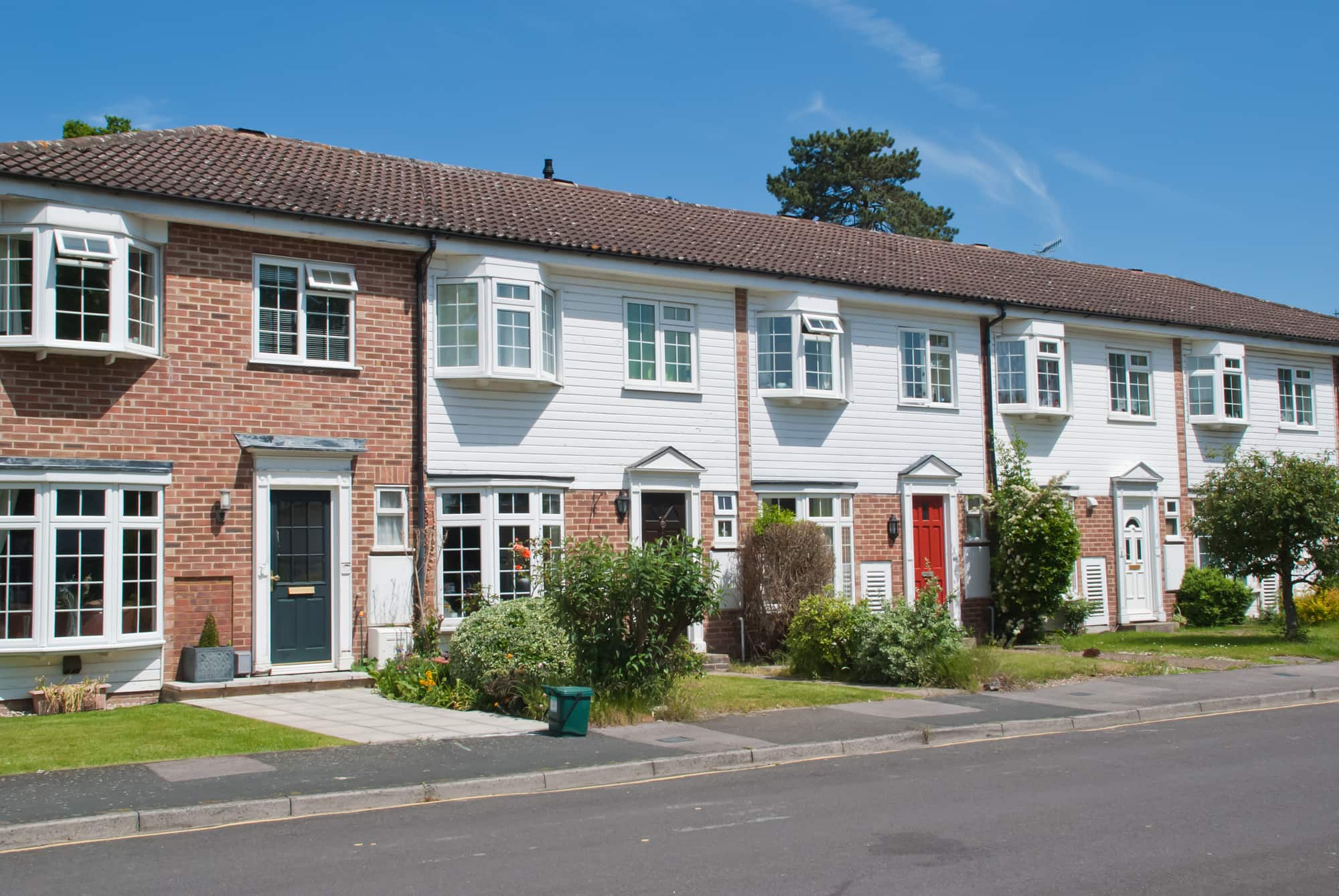 Terraced houses with white cladding, bay windows and small front gardens.